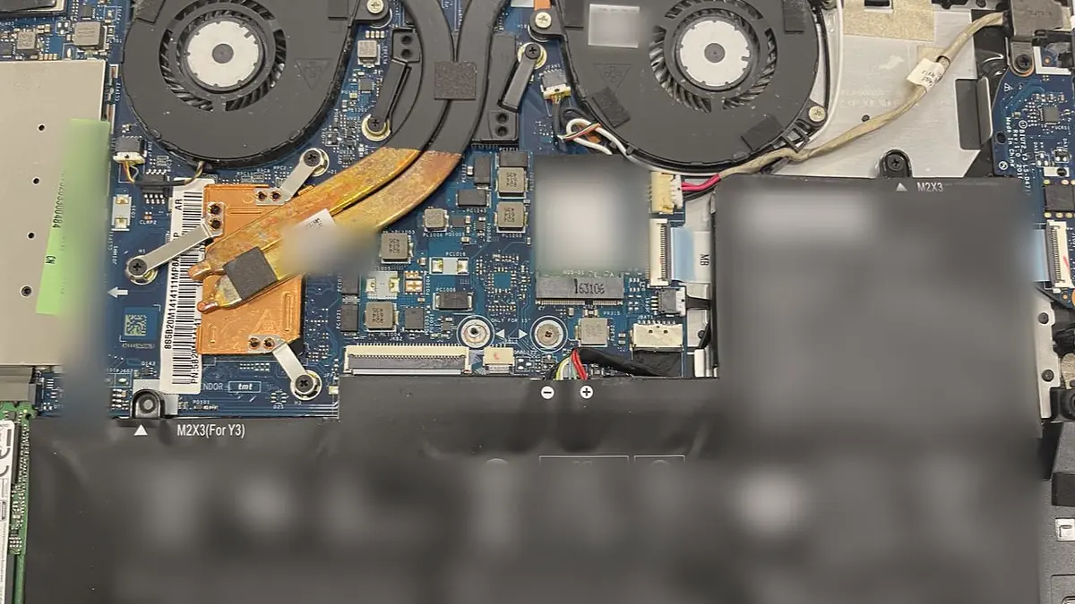Inside an opened laptop, showing the cooling fans, the copper heat pipe and the mainboard