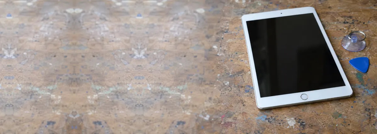 An Apple iPad beside a suction cup and an opening pick on a wooden bench