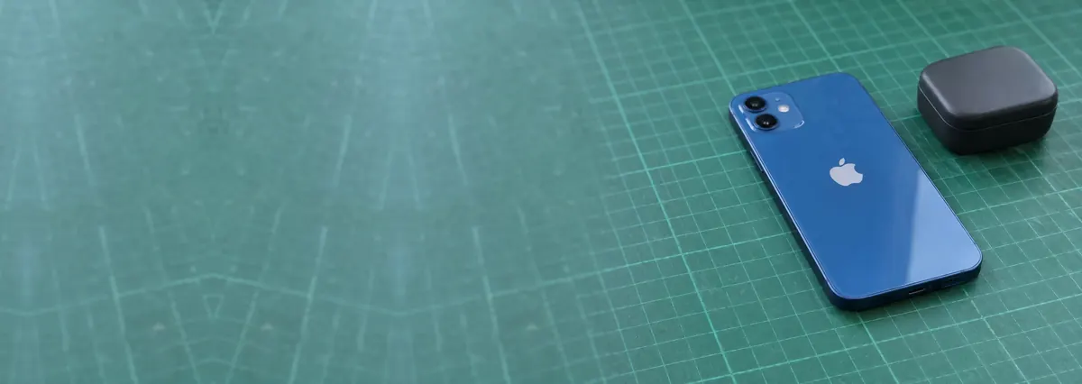 A blue Apple iPhone 14 lying face-down on a green cutting mat