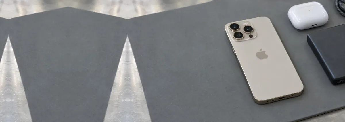 A pale desert-titanium Apple iPhone lying face-down on a grey anti-static mat