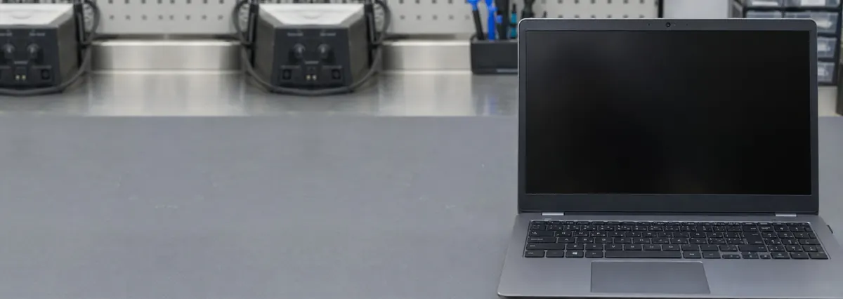 An open laptop with its webcam area in focus and its screen off on a grey anti-static mat
