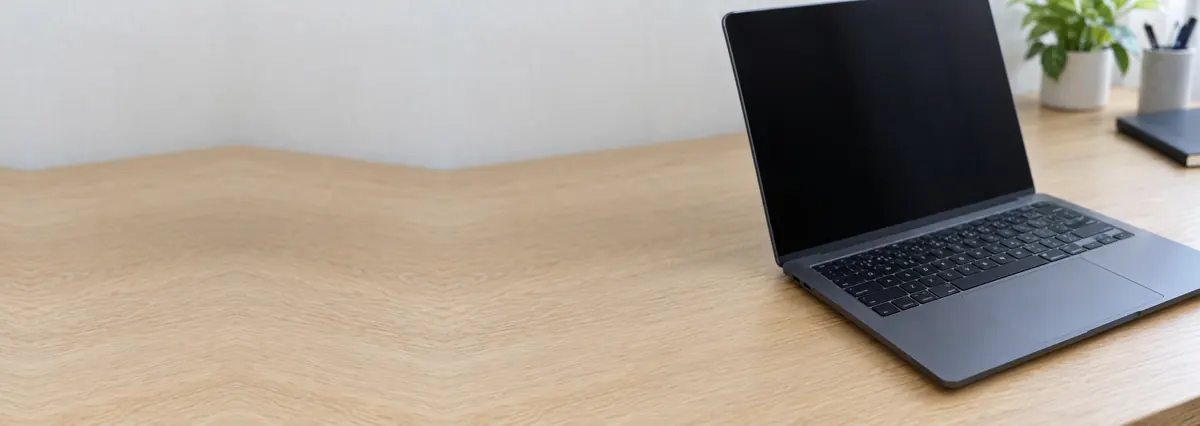 An open dark laptop with its screen switched off on an oak desk top
