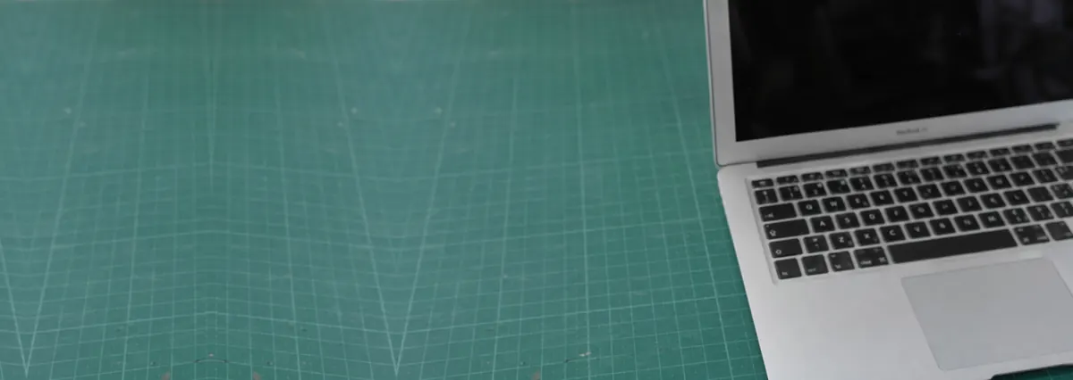 An open silver Apple MacBook seen from above with its keyboard softly out of focus on a green cutting mat
