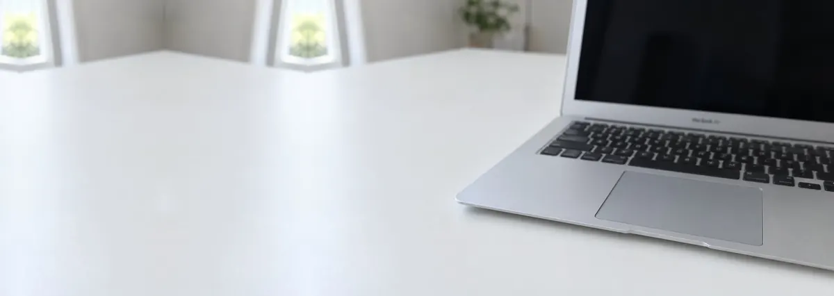 An open silver Apple MacBook with its screen switched off, seen from the front with the trackpad in the foreground